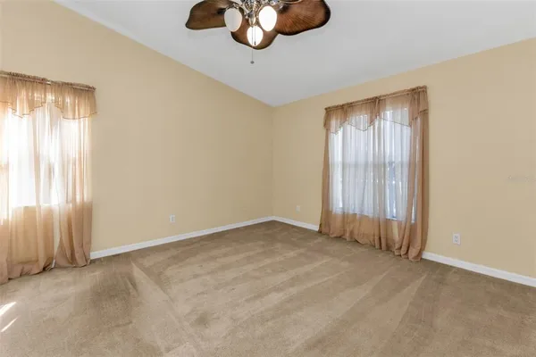 an empty room with windows and chandelier fan