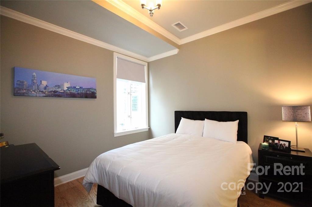 230 South Tryon Street, Unit 304 Charlotte, NC 28281 - Photo 11 of 17 a bedroom with a bed and a night stand