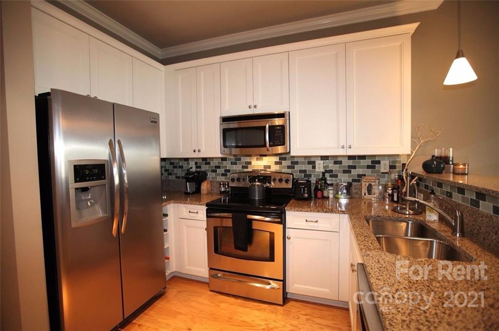230 South Tryon Street, Unit 304 Charlotte, NC 28281 - Photo 3 of 17 a kitchen with stainless steel appliances granite countertop a stove a refrigerator and a microwave