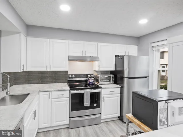 a kitchen with stainless steel appliances granite countertop a sink stove and cabinets