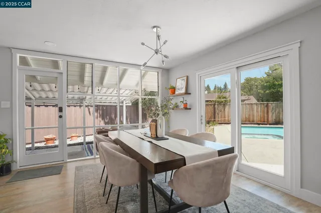 a dining room with furniture large windows and wooden floor