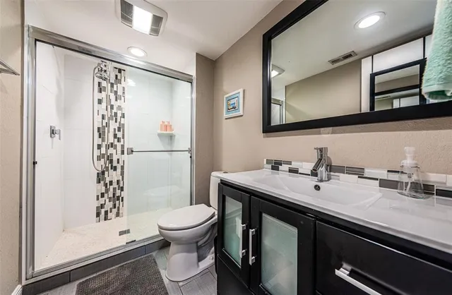 a bathroom with a sink a toilet a mirror and shower