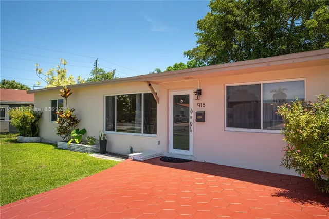 a front view of a house with a yard and potted plants