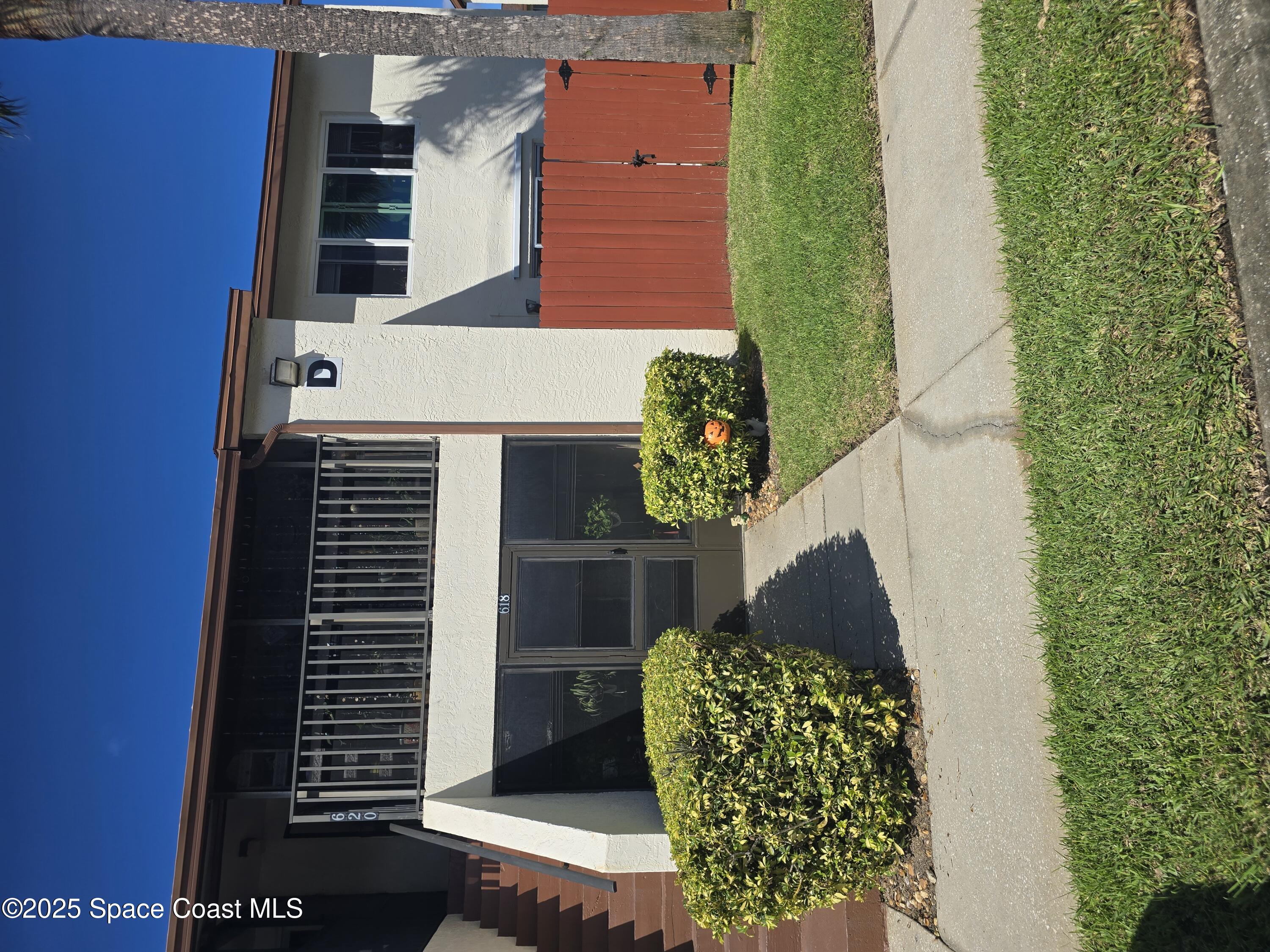 a view of house with a yard and potted plants