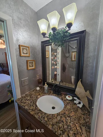 a bathroom with a granite countertop sink a light fixture and a mirror