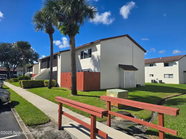 a wooden bench sitting in front of a house with a yard