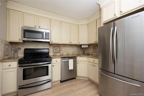 a kitchen with stainless steel appliances granite countertop a stove a refrigerator and a microwave