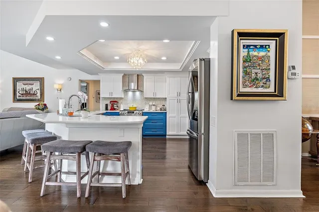 a kitchen with stainless steel appliances granite countertop a refrigerator a stove a sink a dining table and chairs with wooden floor