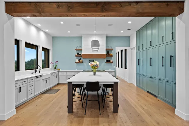 a kitchen with stainless steel appliances kitchen island granite countertop a table chairs sink and cabinets
