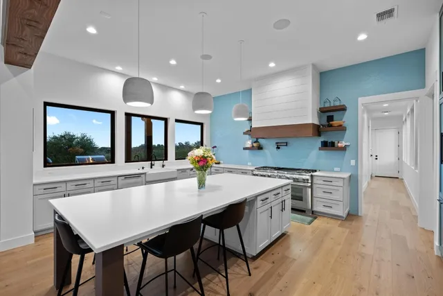 a kitchen with stainless steel appliances granite countertop a stove top oven a sink dishwasher a dining table and chairs with wooden floor