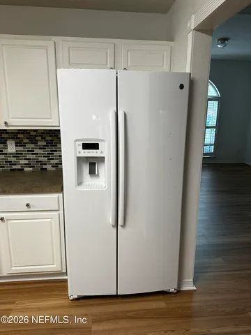 a close view of a refrigerator in kitchen and white cabinets