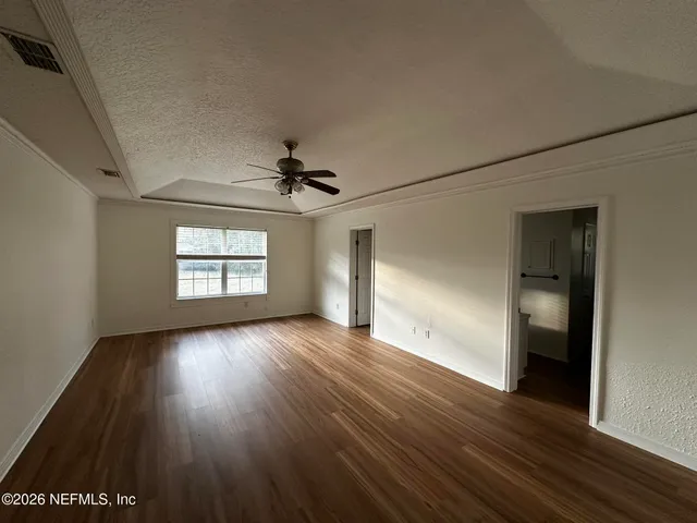 an empty room with wooden floor chandelier and windows