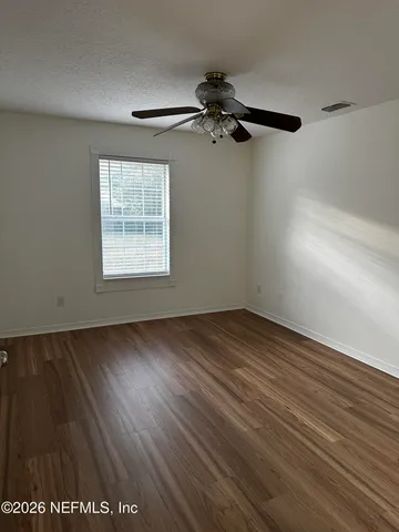 an empty room with wooden floor cabinet and windows