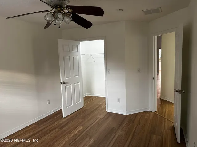 an empty room with wooden floor closet and windows