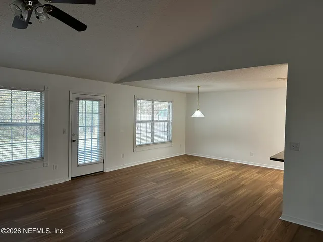 an empty room with wooden floor and windows