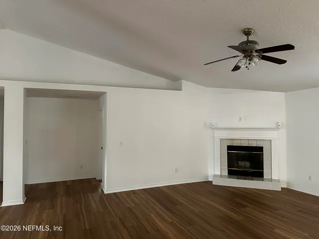 a view of empty room with wooden floor and fireplace