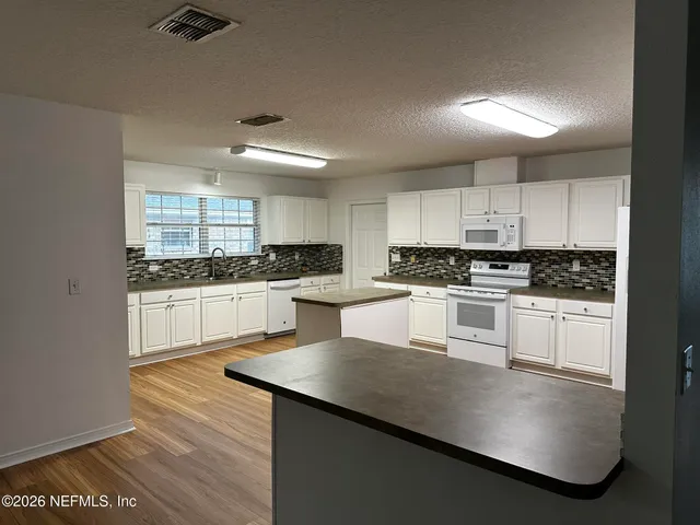 a kitchen with granite countertop white cabinets and white appliances