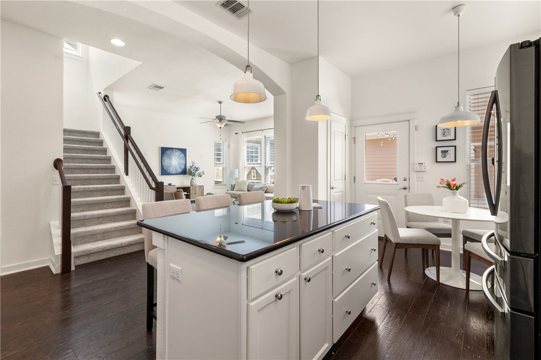 a kitchen with stainless steel appliances kitchen island granite countertop a table chairs refrigerator and a sink