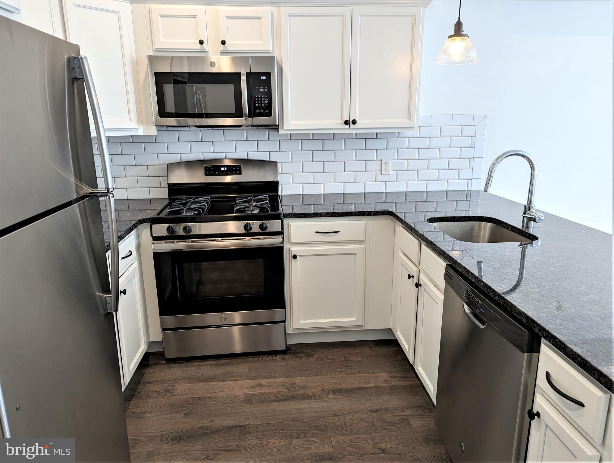 6615 Ridge Avenue, Unit 304 Philadelphia, PA 19128 - Photo 3 of 10 a kitchen with stainless steel appliances a sink a stove a microwave and cabinets