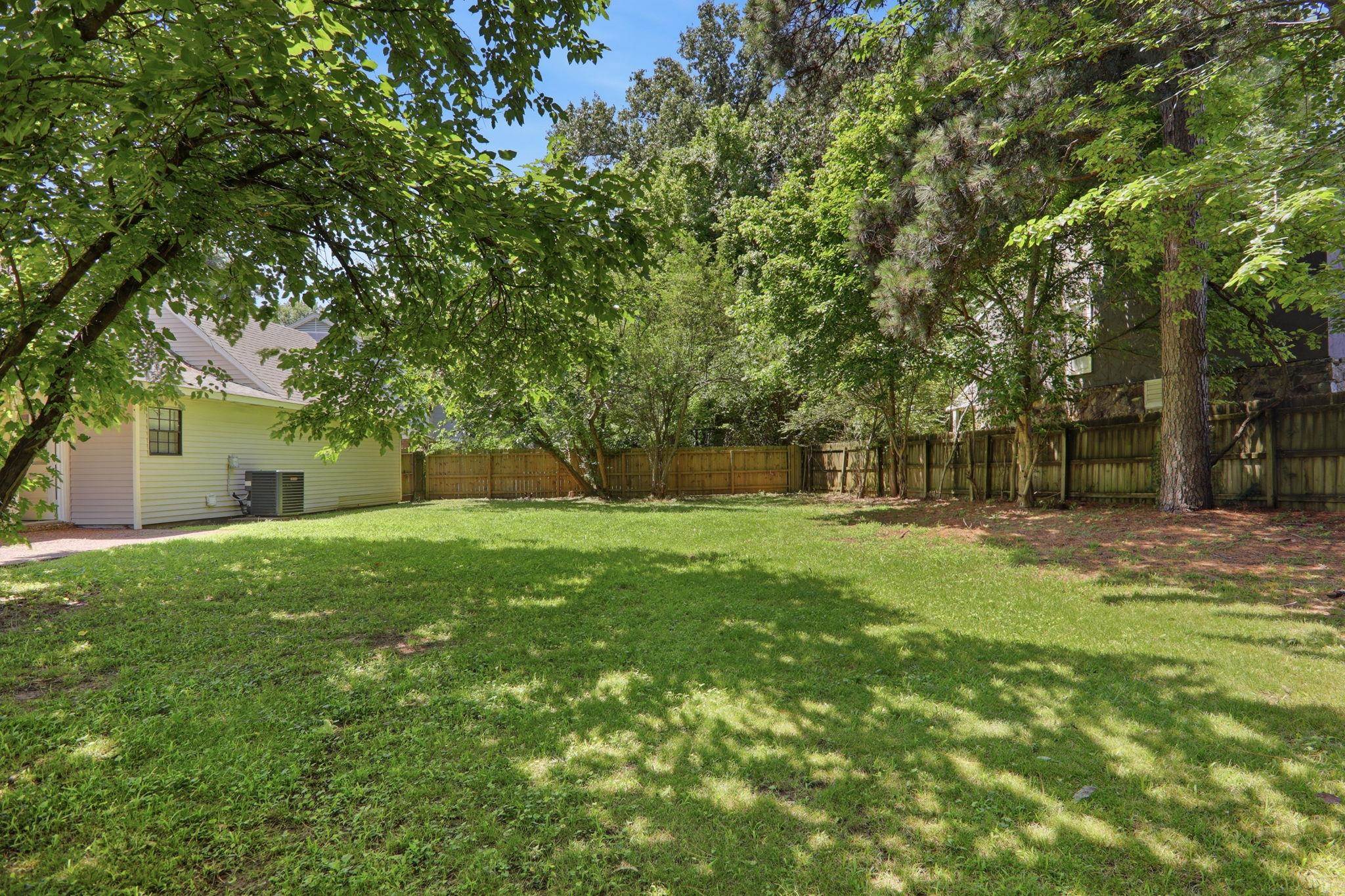 3113 Raleigh Ridge Cove Memphis, TN 38128 - Photo 38 of 38 Expansive fenced backyard featuring a substantial lawn area, mature trees providing natural shade, and a privacy fence enclosing the perimeter