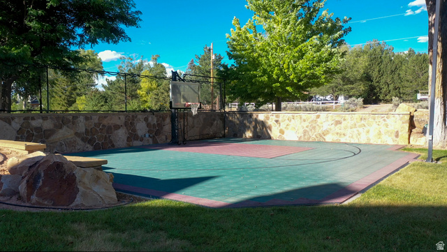 426 West Center Street Parowan, UT 84761 - Photo 78 of 107 Outdoor sport court featuring a basketball hoop, multi-colored modular tile surface, and a stone retaining wall
