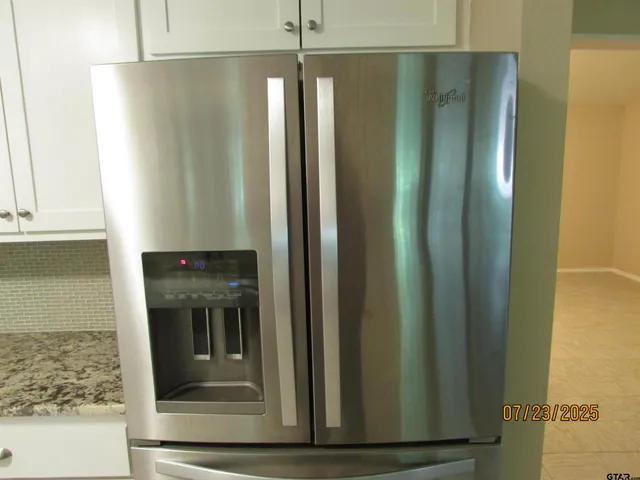 a kitchen with stainless steel appliances granite countertop a dining table chairs refrigerator and sink