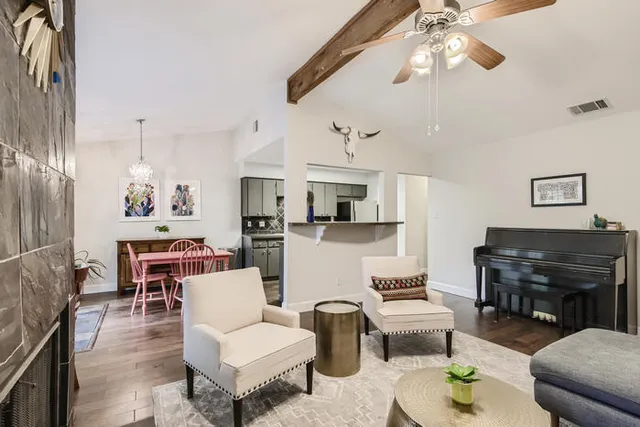 a living room with furniture kitchen view and a chandelier