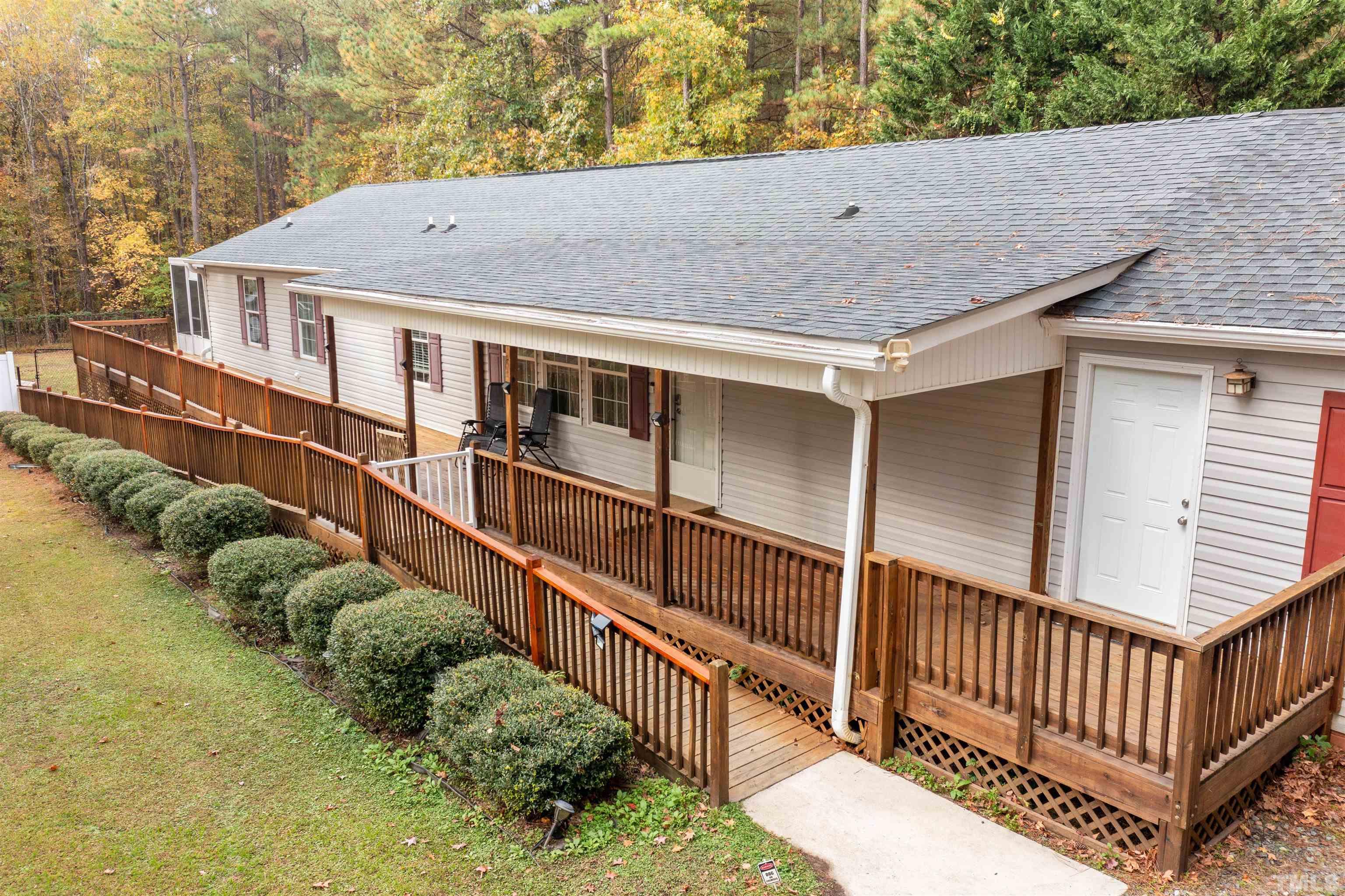 a view of house with wooden deck and a backyard
