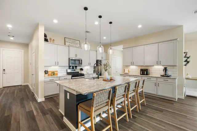 a kitchen with a stove a refrigerator and white cabinets with wooden floor