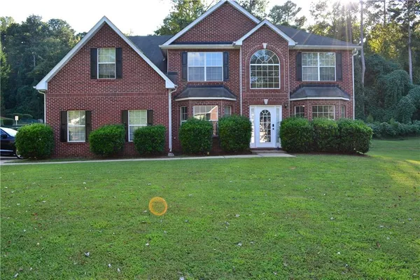a view of a brick house with a big yard and potted plants