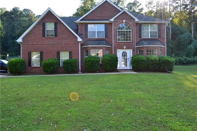 a view of a brick house with a big yard and potted plants