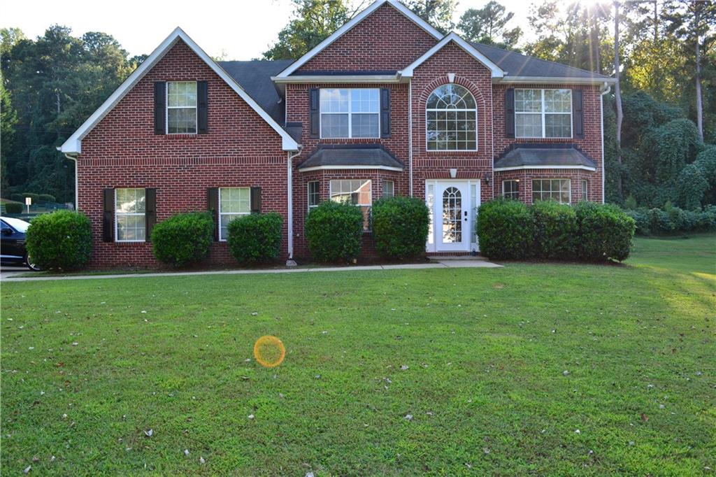 a view of a brick house with a big yard and potted plants