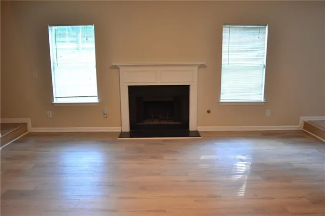 a view of empty room with wooden floor and a fireplace