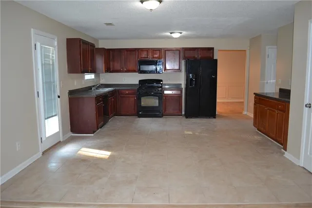a kitchen with granite countertop a refrigerator and a stove top oven