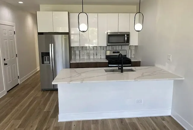 a room with wooden floor potted plant and a chandelier