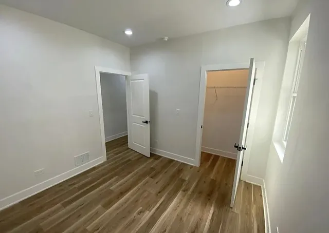 an empty room with wooden floor and a sink