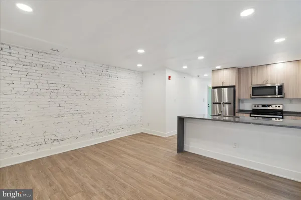 a view of kitchen with stainless steel appliances wooden floor and wooden floor