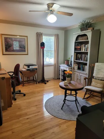 a living room with furniture a piano and a bookshelf