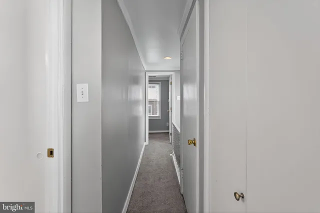 a view of a hallway with wooden floor and a bathroom