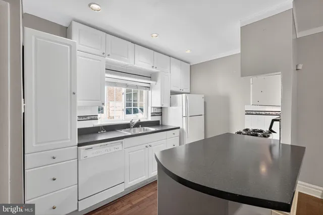 a kitchen with stainless steel appliances granite countertop a sink a refrigerator and white cabinets