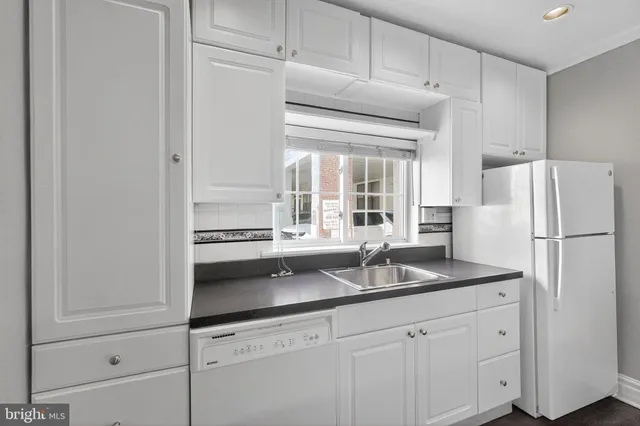 a kitchen with granite countertop a refrigerator and a sink