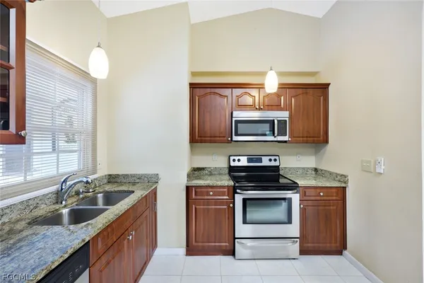 a kitchen with granite countertop a stove top oven sink and cabinets