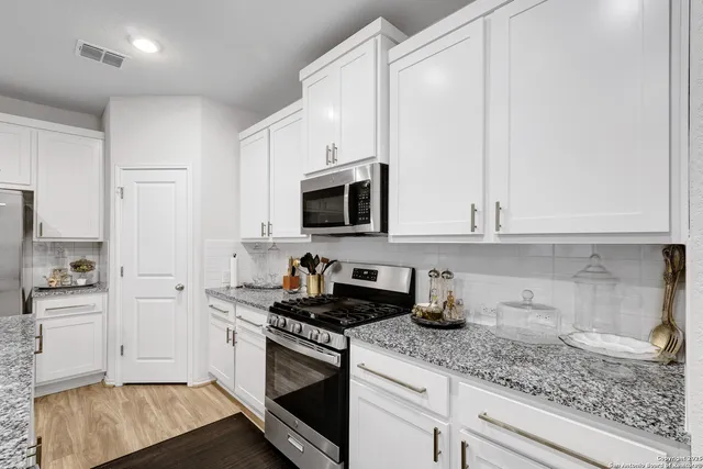 a kitchen with stainless steel appliances granite countertop white cabinets and a stove