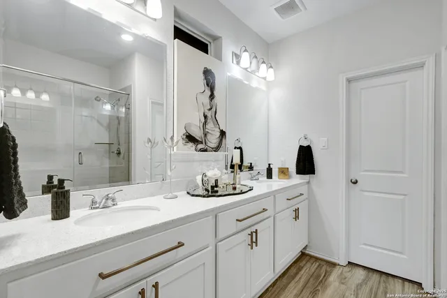 a bathroom with a double vanity sink mirror and shower