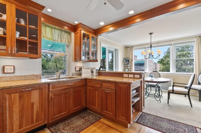 a kitchen with a stove a sink dishwasher and a dining table with wooden cabinet