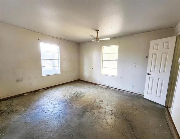 an empty room with windows and ceiling fan view