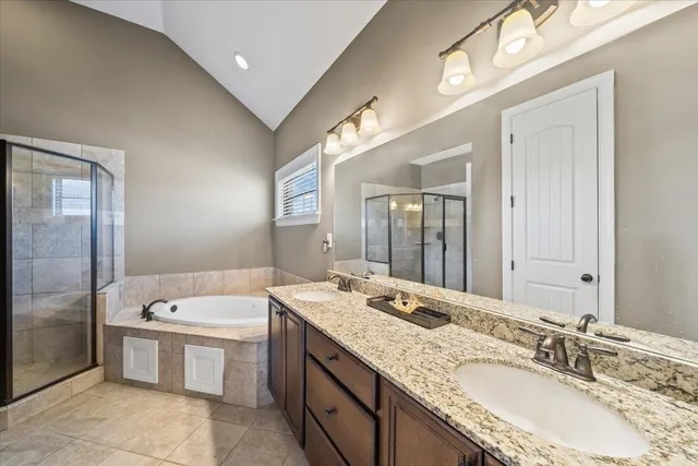 a bathroom with a granite countertop double vanity sink and mirror with bathtub