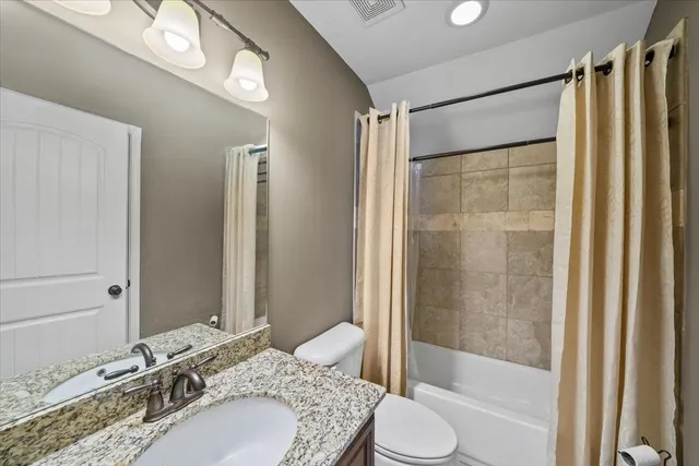 a bathroom with a granite countertop sink toilet and shower