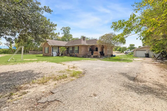 a view of a house with a yard and palm trees