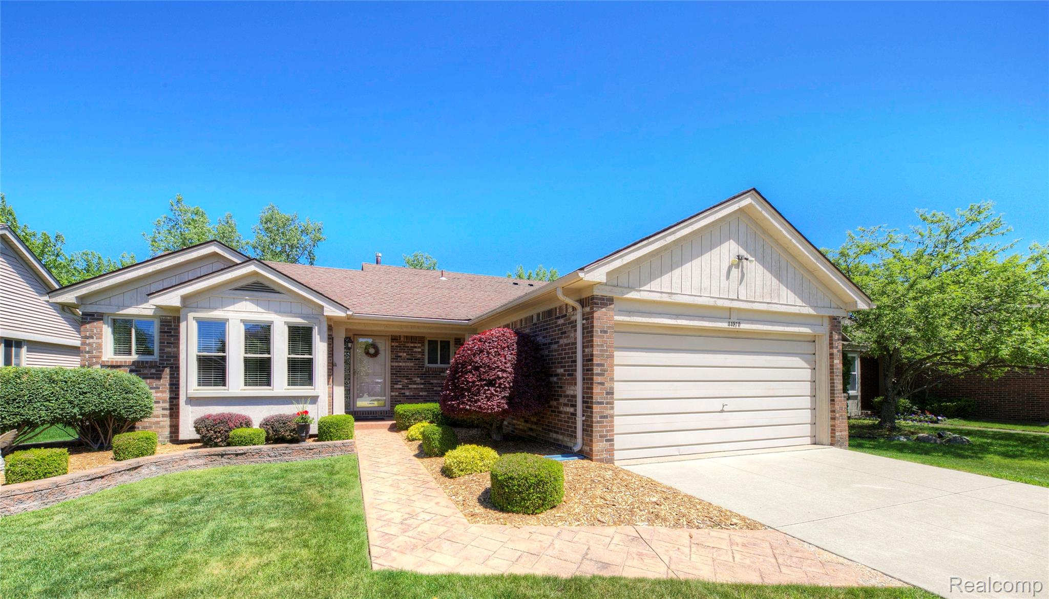 44570 Ridgefield Road Canton, MI 48188 - Photo 2 of 31 Brick and siding exterior featuring a decorative bay window, an attached two-car garage, and a stamped concrete walkway